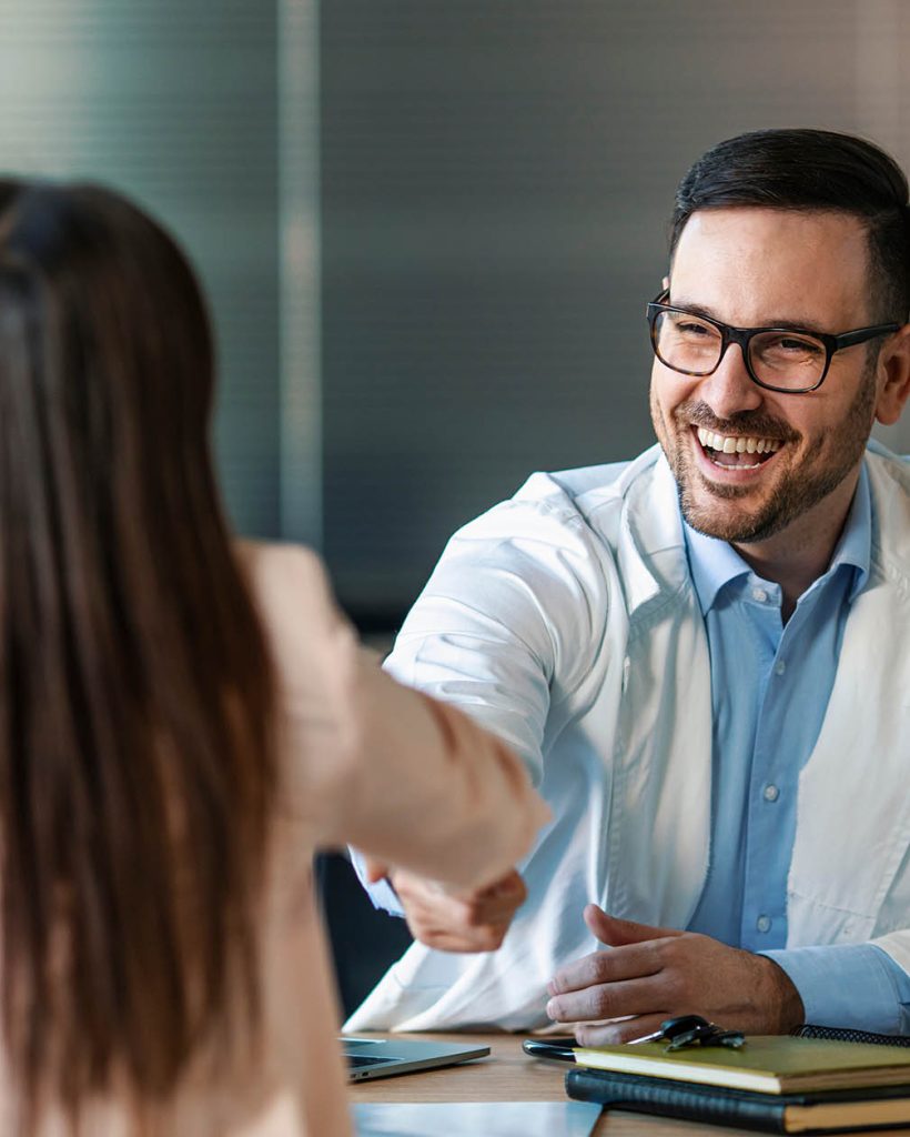 Doctor shaking hands with woman. Female patient visiting health professional. They are in hospital. Cropped shot of a handsome young male doctor and his patient shaking hands in the hospital